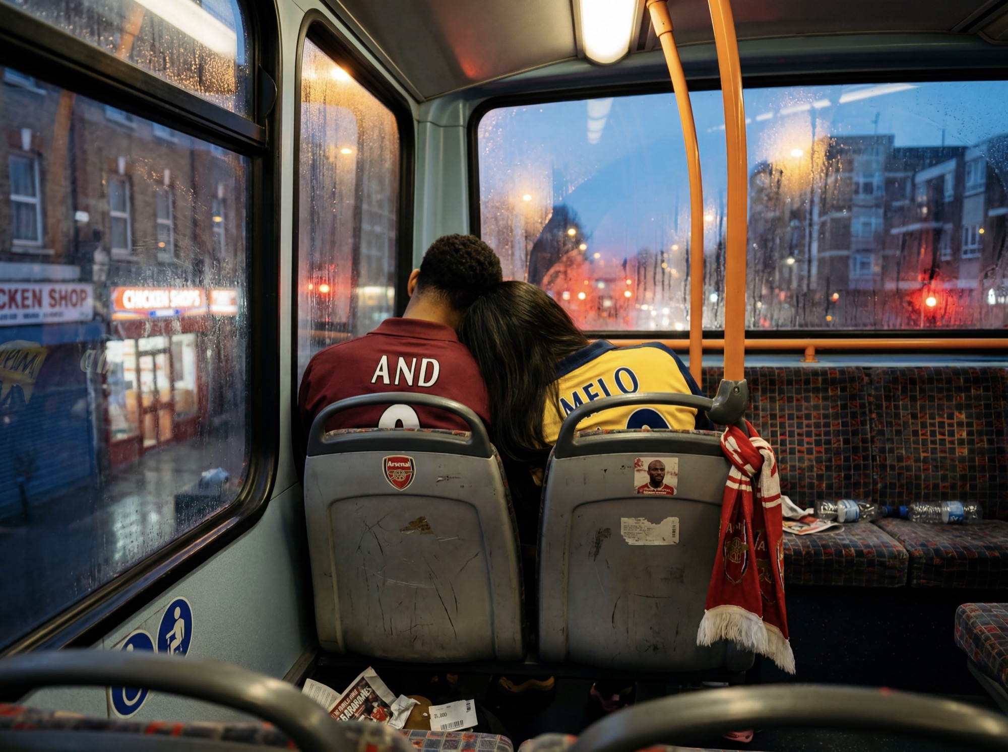 Two scarves over empty bus seats, high street outside
