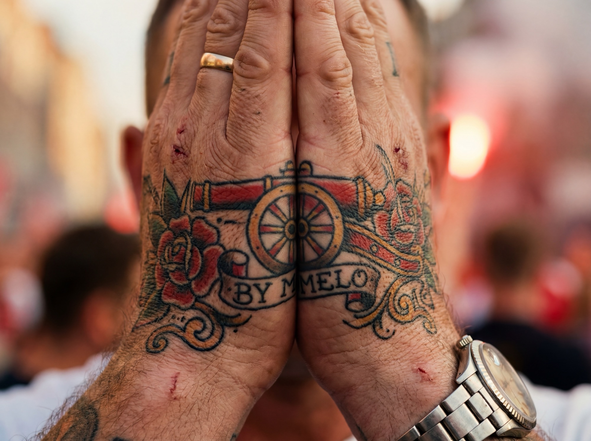 A supporter's hands together, the cannon tattooed across the fingers