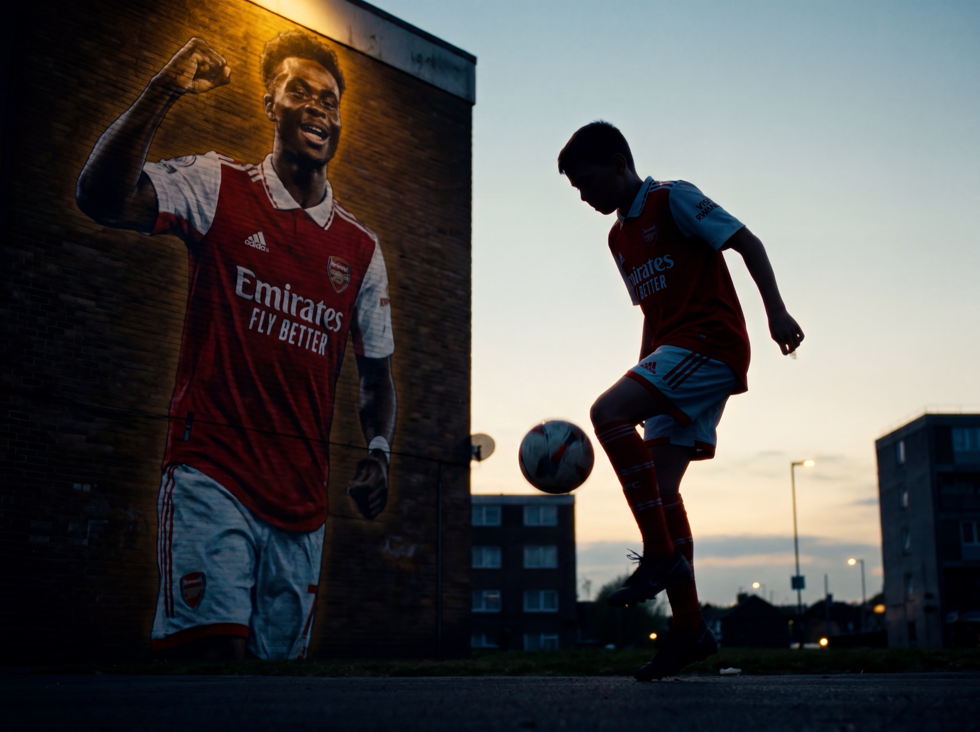 A child playing beneath a mural at dusk