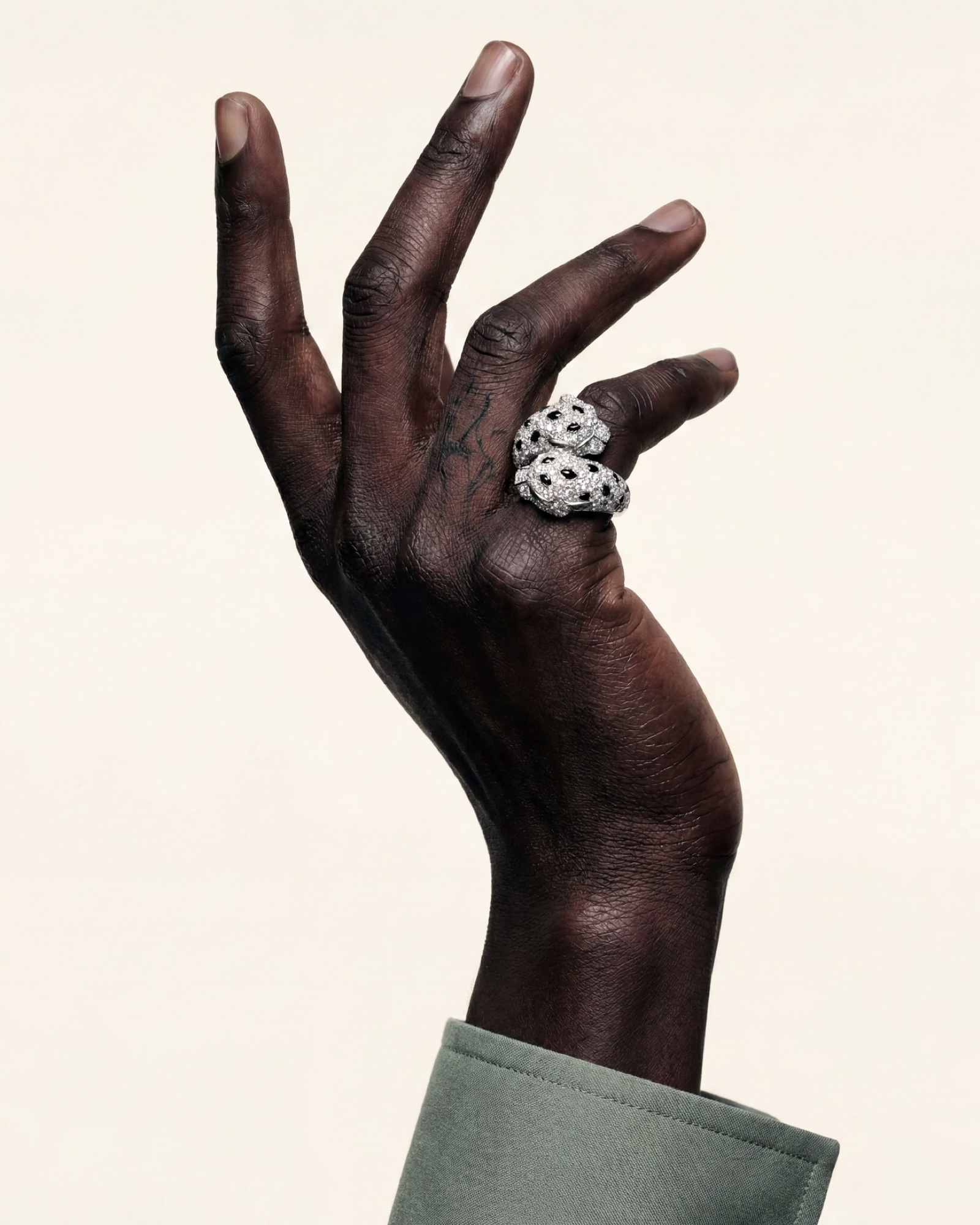 A raised hand against a bare ground, panther ring on the finger