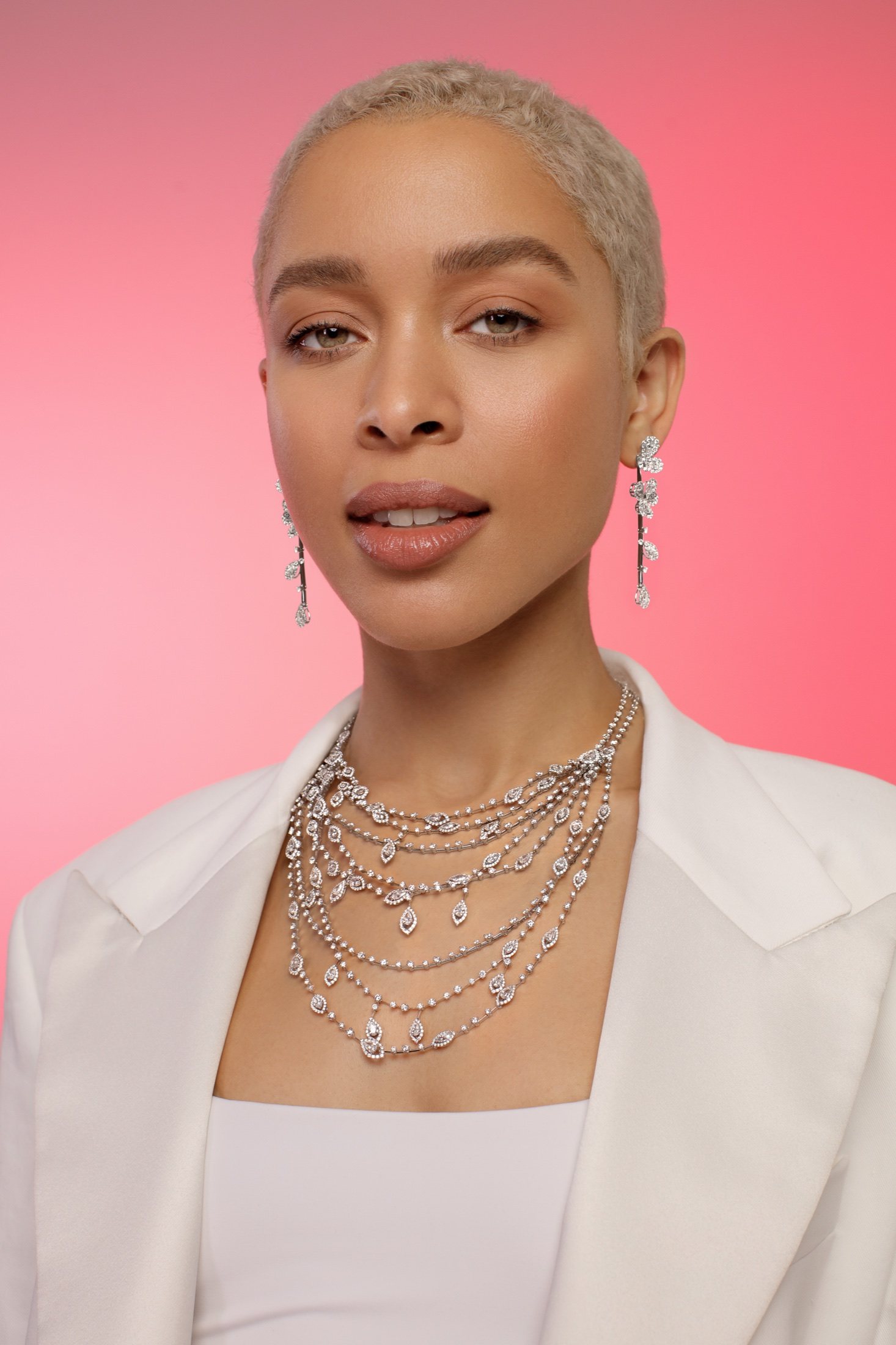 Layered diamond necklaces on a pink gradient