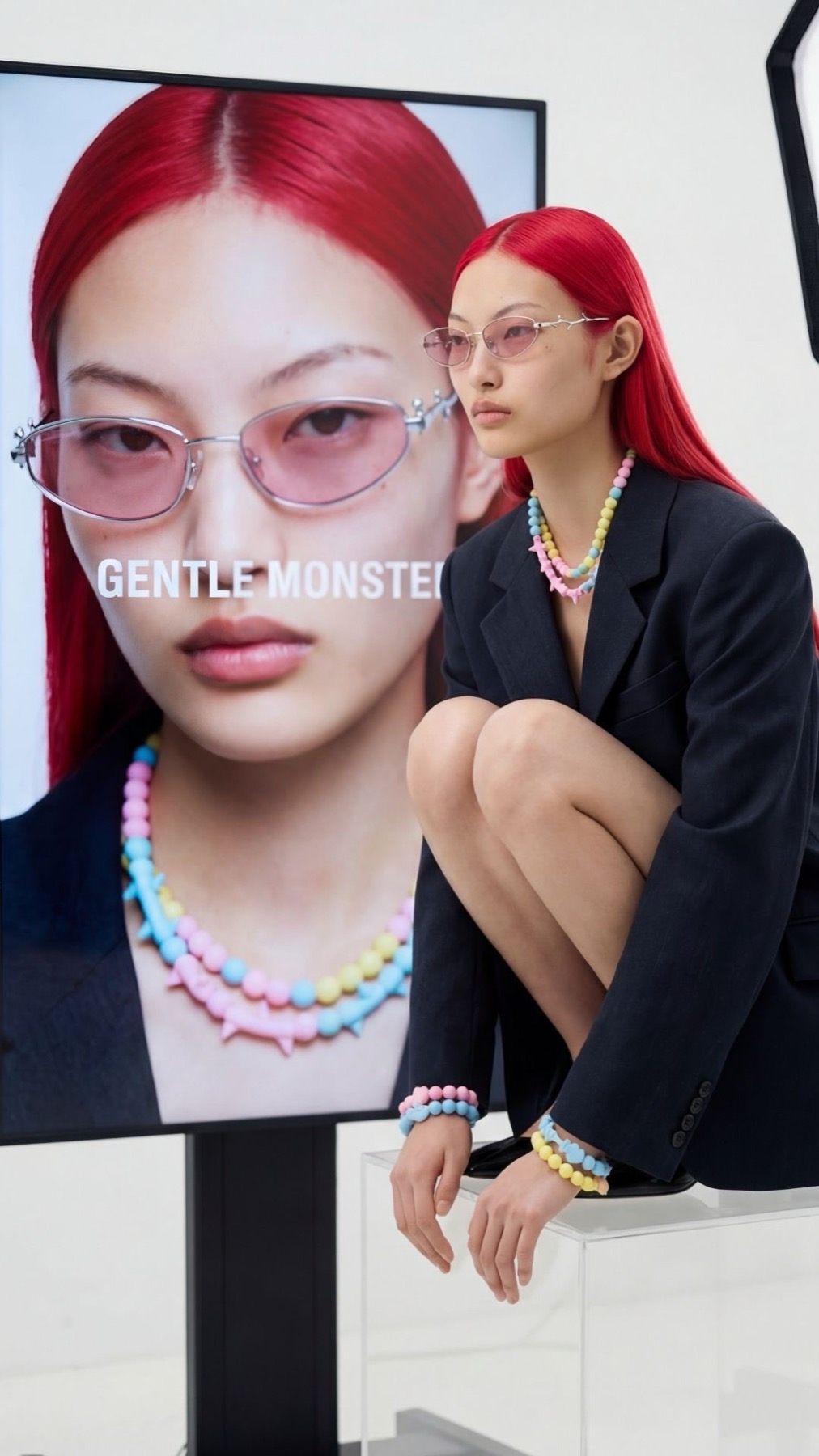 Heartwear campaign running on an in-store screen beside a model wearing the Digital Romance frame