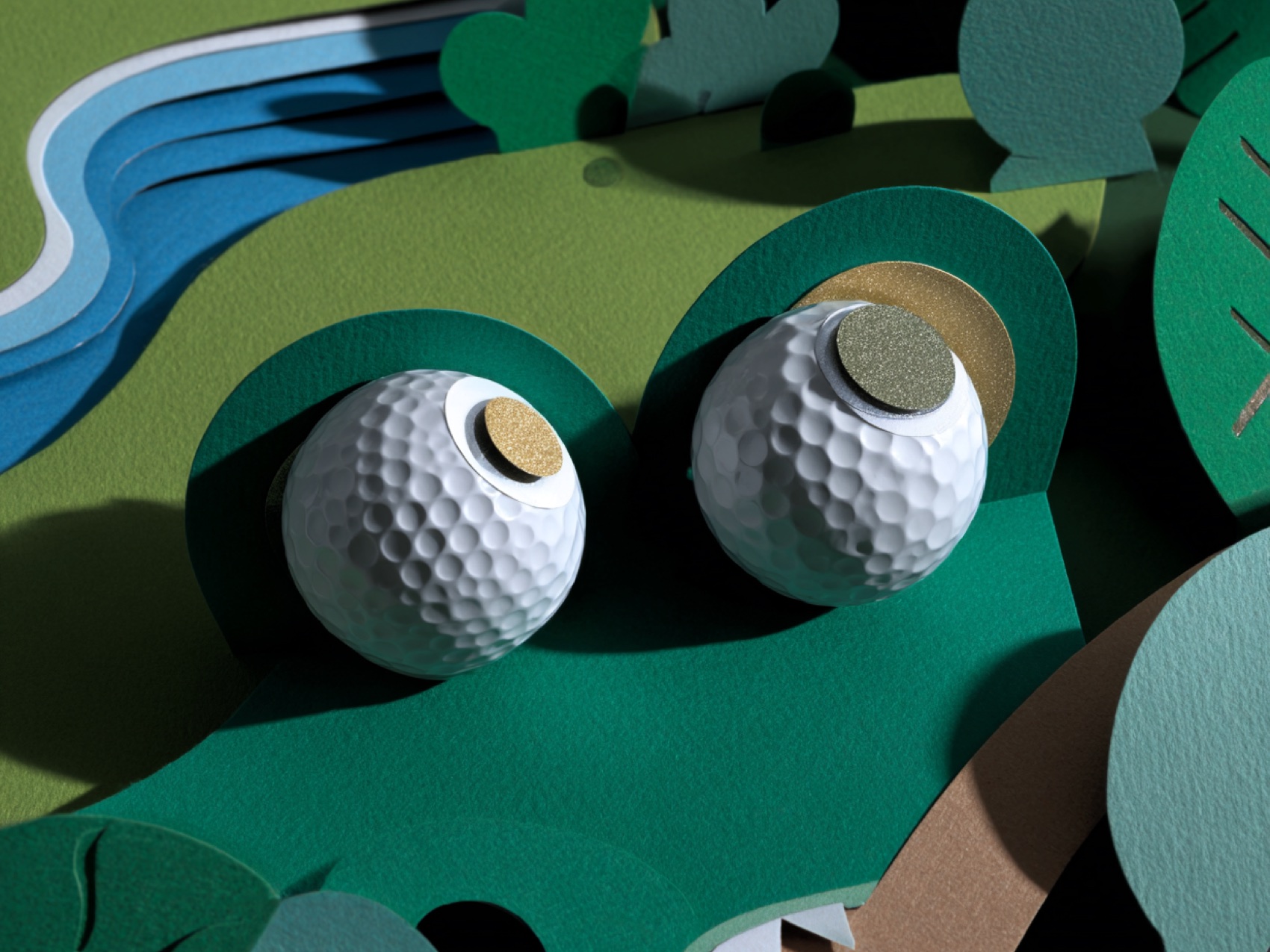 Two paper golf balls resting in paper rough