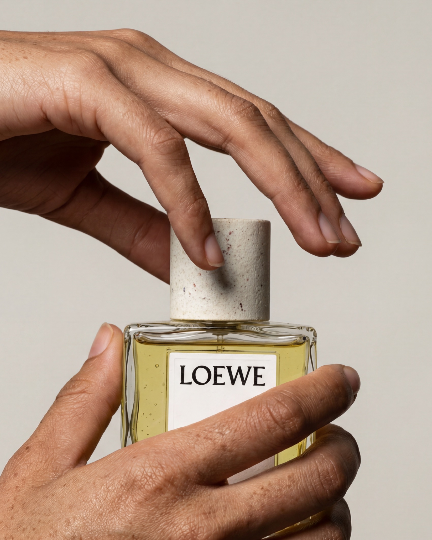 A hand lifting the stone cap from the bottle