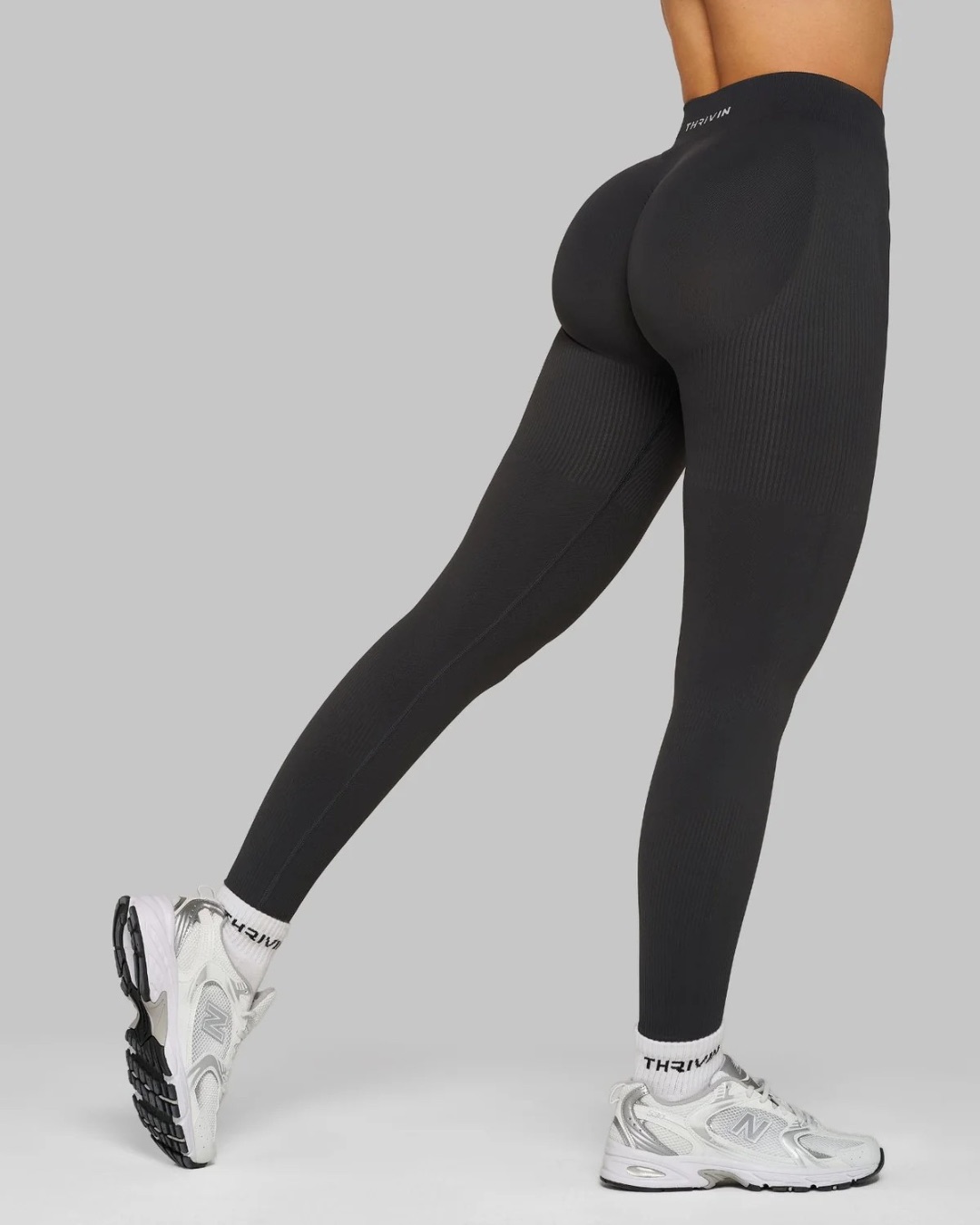 Thrivin wordmark on a legging waistband, shot against a neutral ground