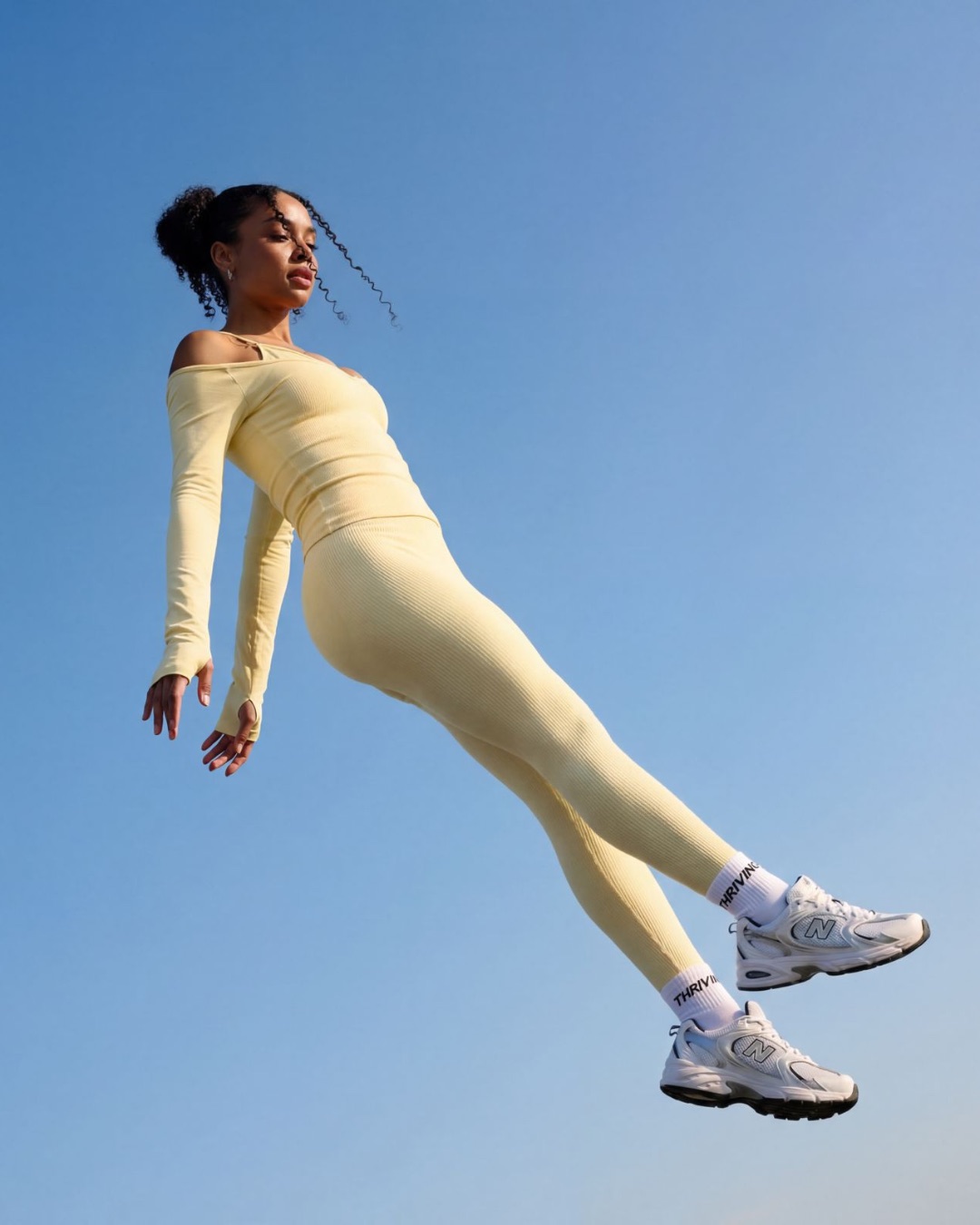 Thrivin campaign frame: a model suspended against blue sky, arms trailing