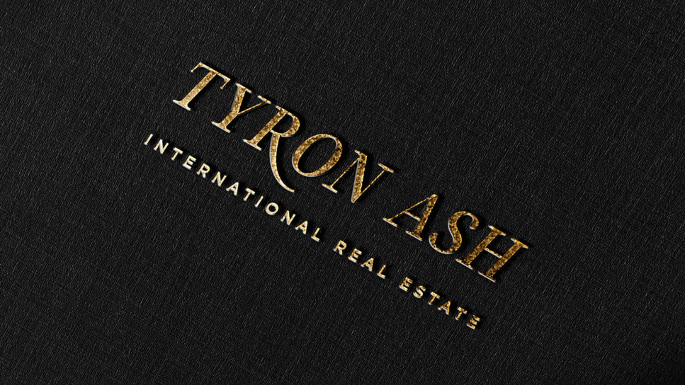 The Tyron Ash mark in gold foil on textured black stock